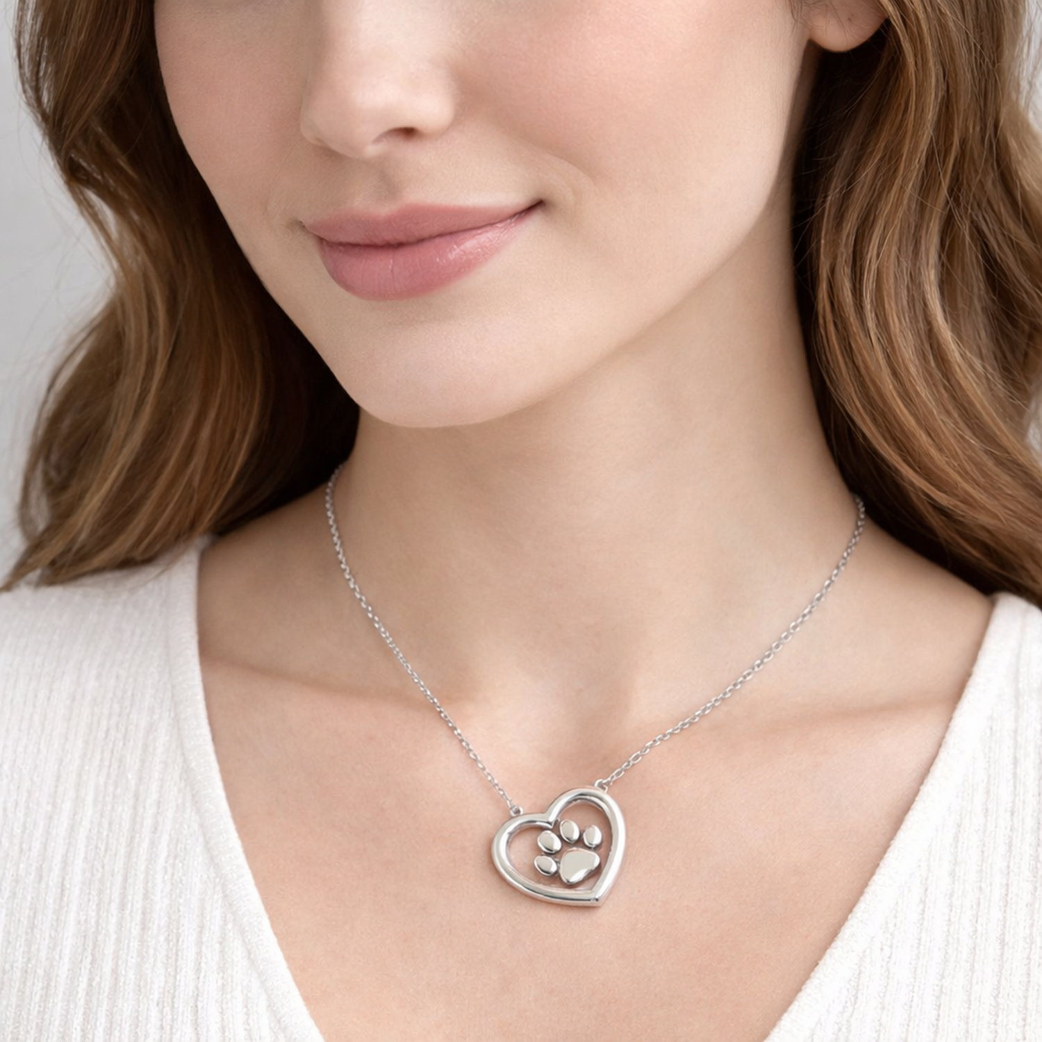 Sterling silver paw print necklace with heart pendant worn by woman from Melchior Jewellery