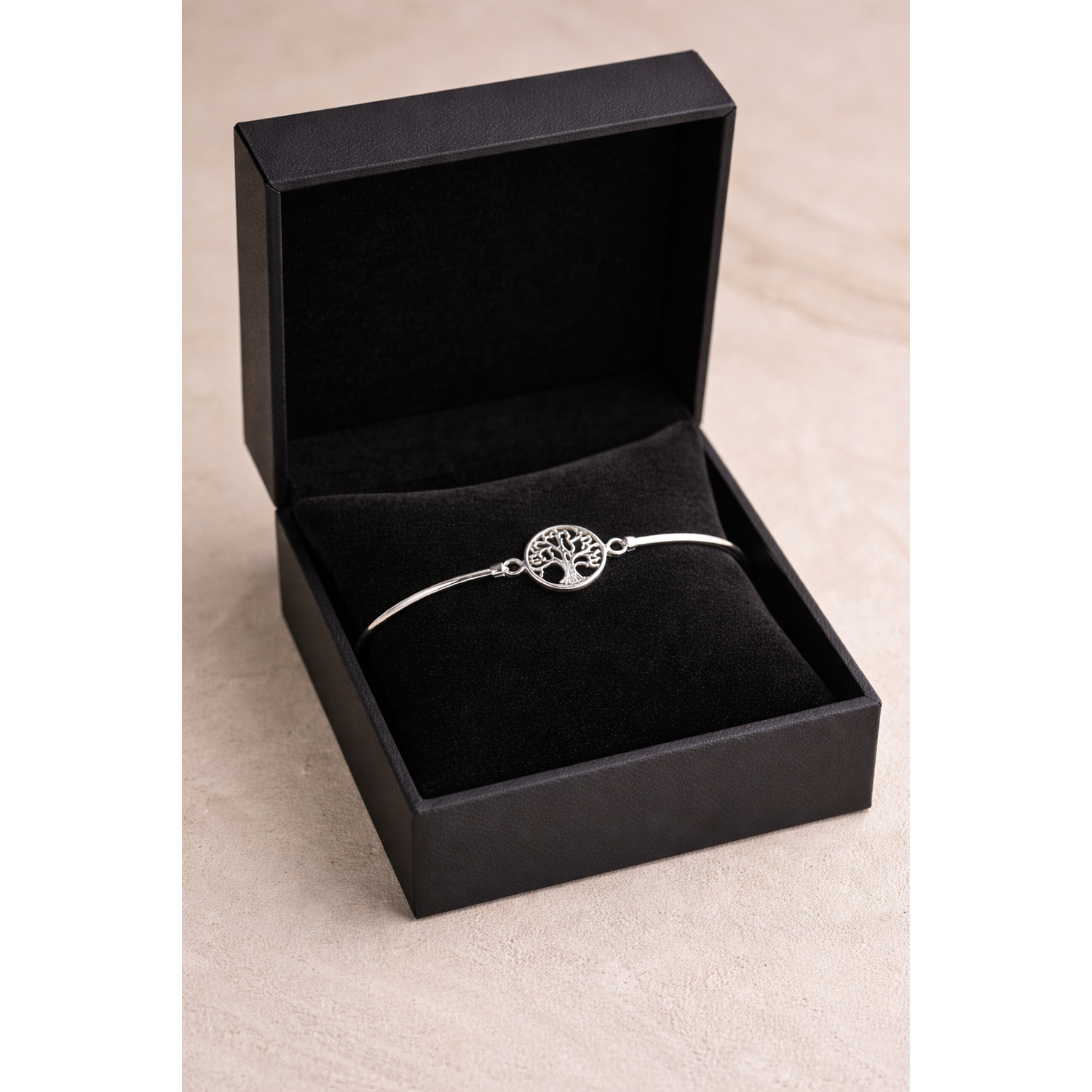 Sterling silver tree of life bangle by Melchior Jewellery displayed in a black gift box on a beige surface