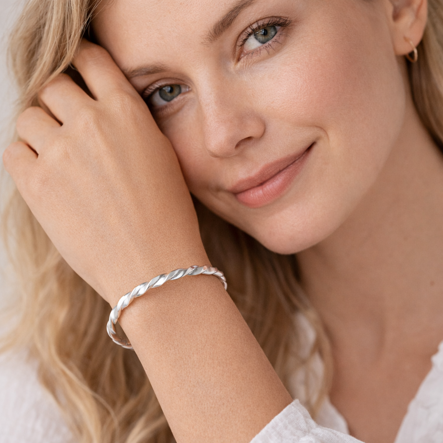 Melchior Jewellery sterling silver twisted cuff bangle worn on wrist by woman with light skin and blonde hair