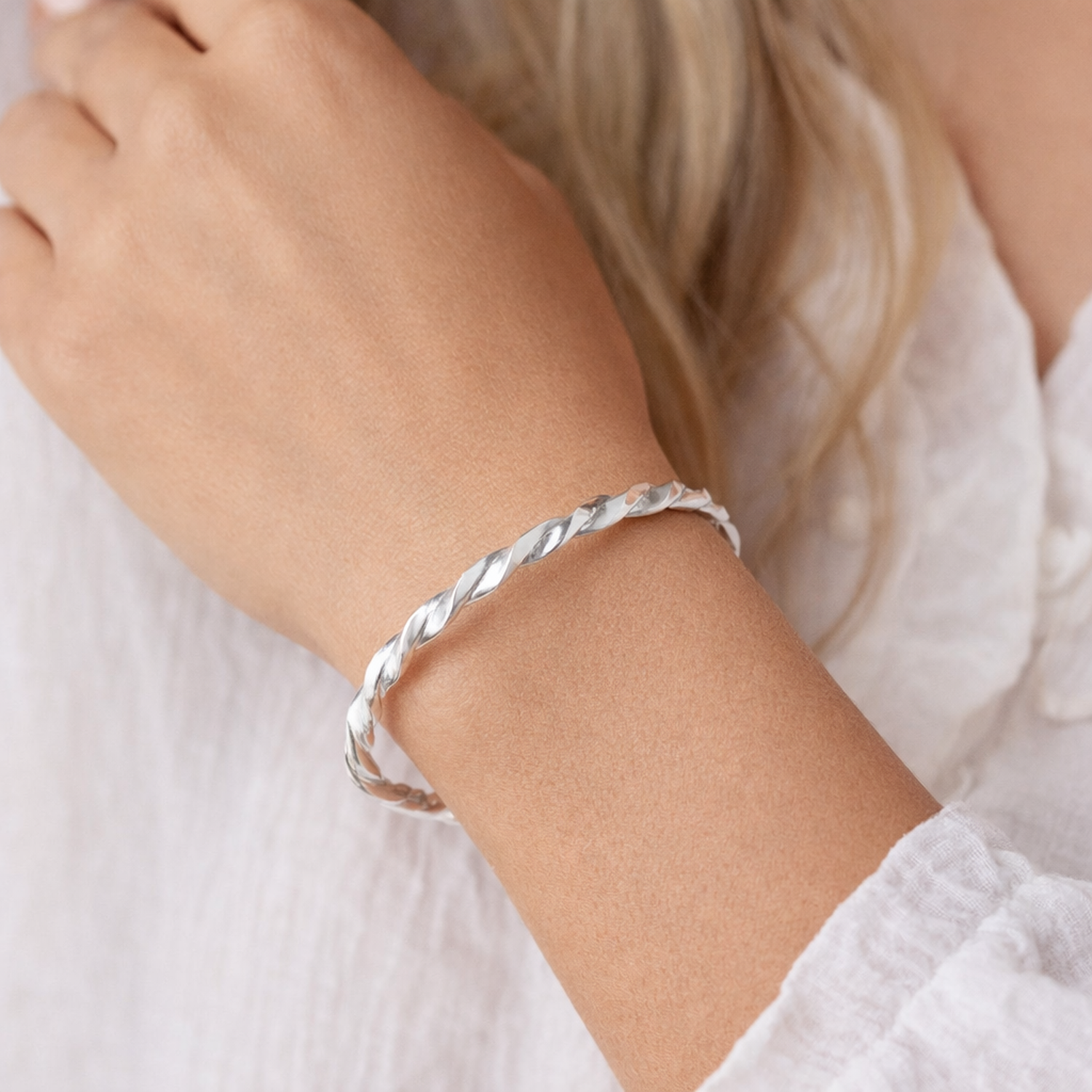 Melchior Jewellery sterling silver twisted cuff bangle worn on wrist with white blouse