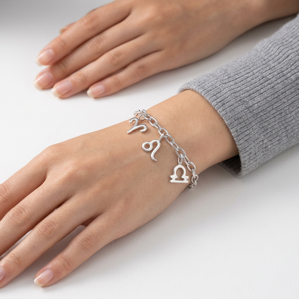 Sterling silver zodiac charm bracelet with Aries Leo and Libra symbols on model wrist