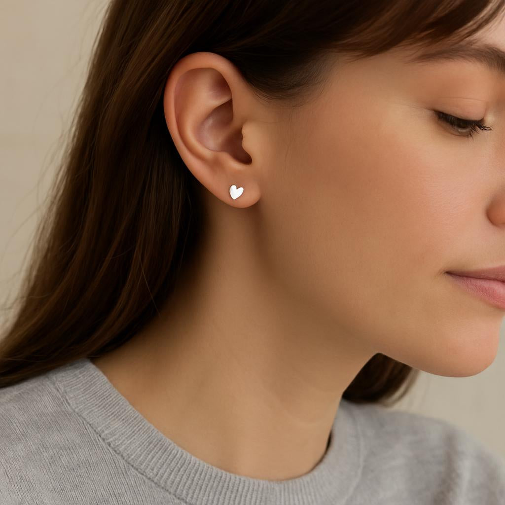 Melchior Jewellery titanium heart stud earrings worn by woman with brown hair and grey top