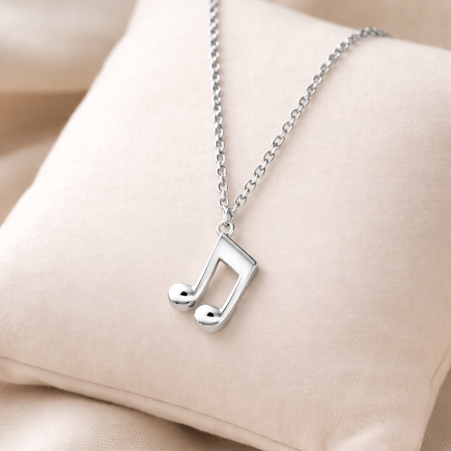 Sterling silver music note necklace from Melchior Jewellery displayed on a soft cushion