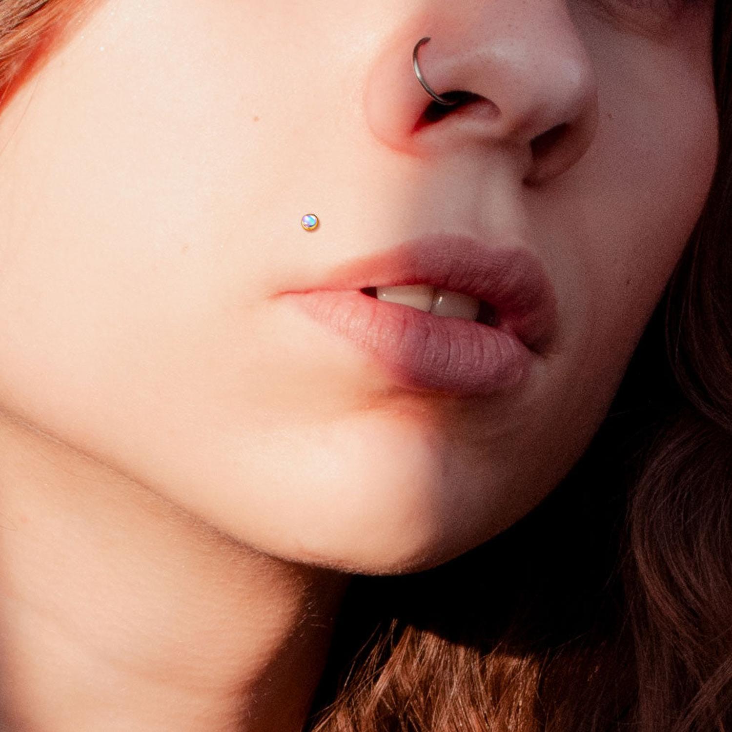 Melchior Jewellery flat back labret with iridescent stone worn on a cheek piercing close up