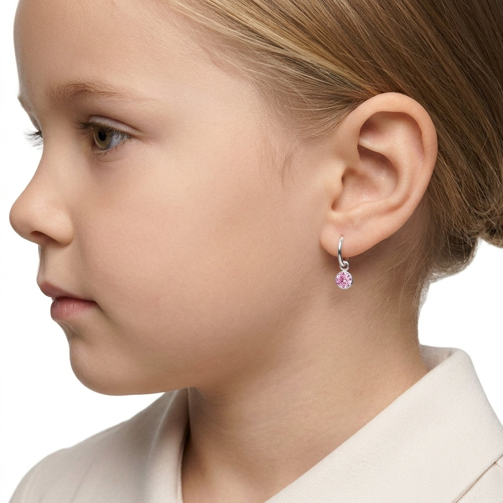 Sterling Silver Hoop Earrings with small pink gemstone charm worn by child with blonde hair