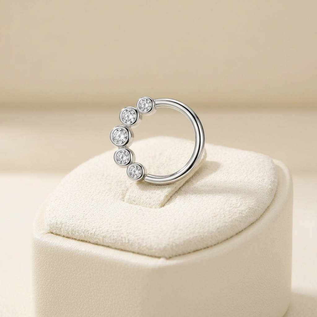 Sterling silver cartilage hoop with five clear stones displayed on cream jewellery cushion