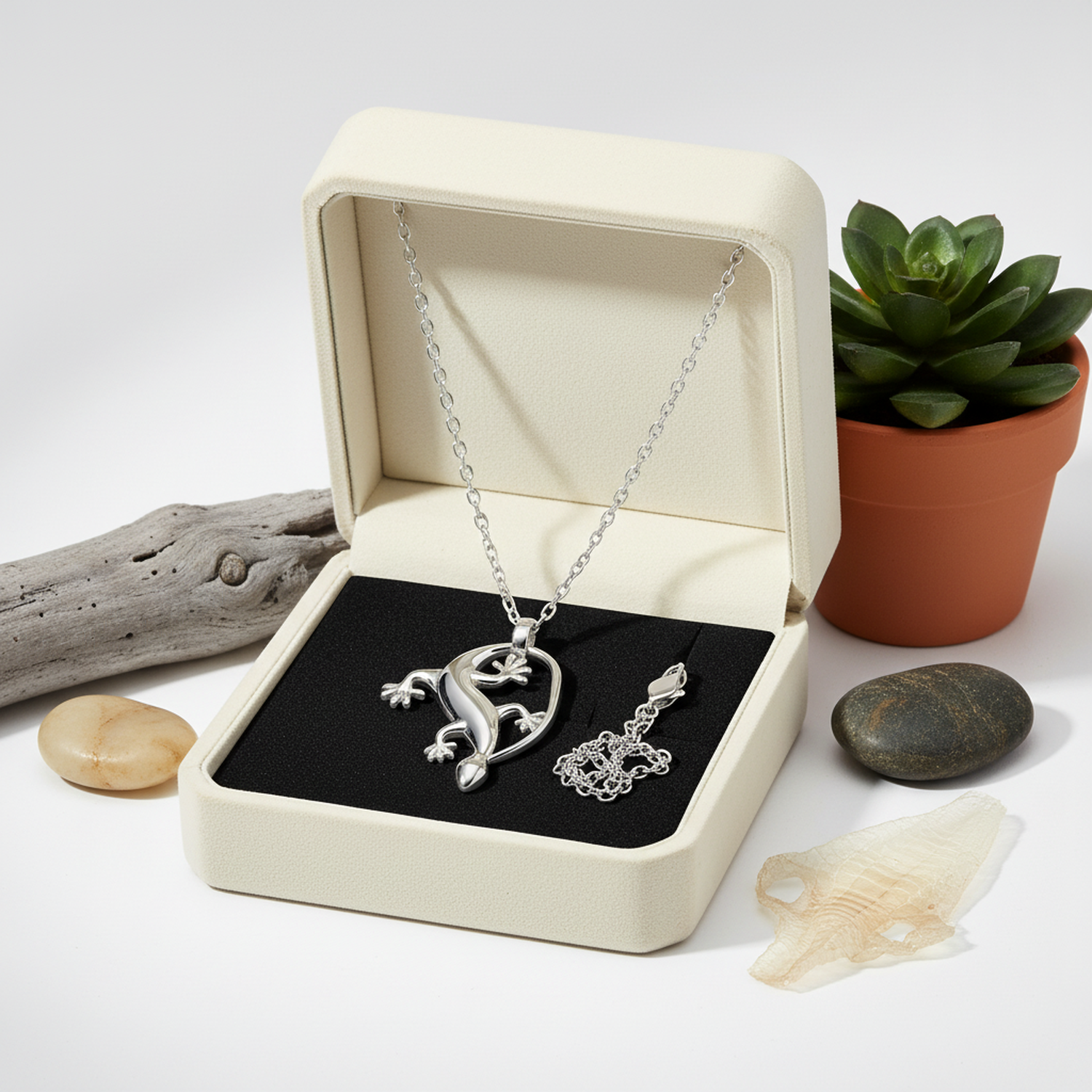 Silver gecko charm necklace from Melchior Jewellery displayed in elegant cream box with chain and decorative elements