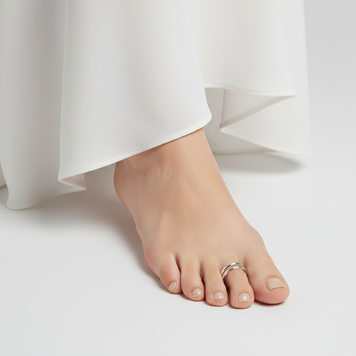 Melchior Jewellery silver double band toe ring worn on bare foot with white flowing garment