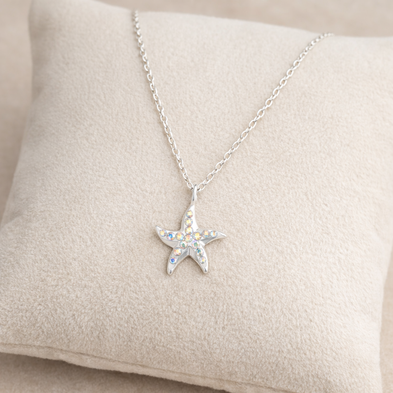 Melchior Jewellery sterling silver starfish necklace with iridescent stones on soft beige cushion