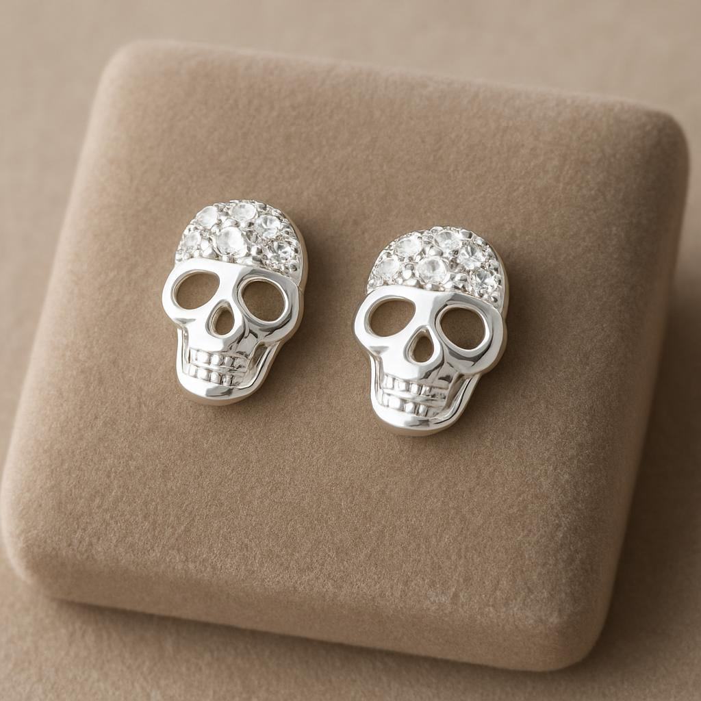 Melchior Jewellery sterling silver skull stud earrings with crystal accents on beige cushion