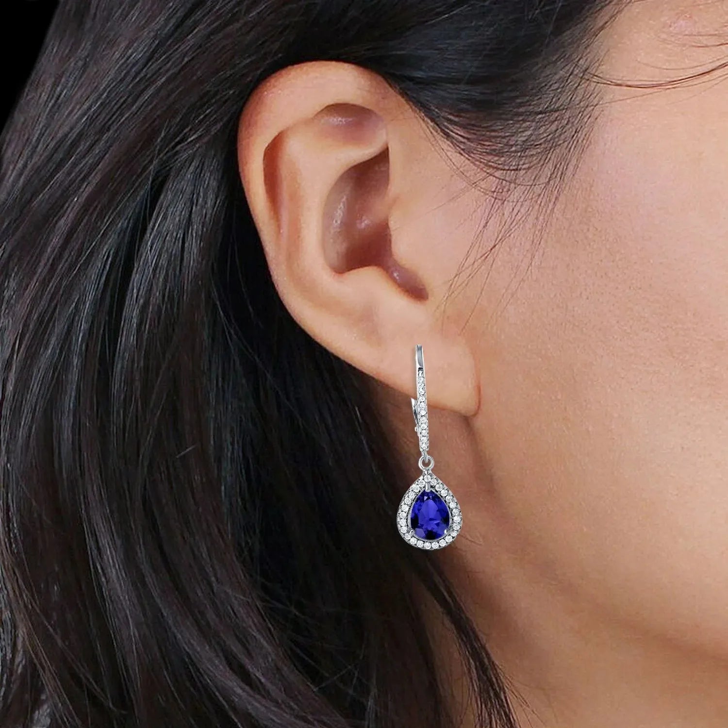 Sterling silver sapphire earrings by Melchior Jewellery worn on woman's ear with teardrop sapphire pendant