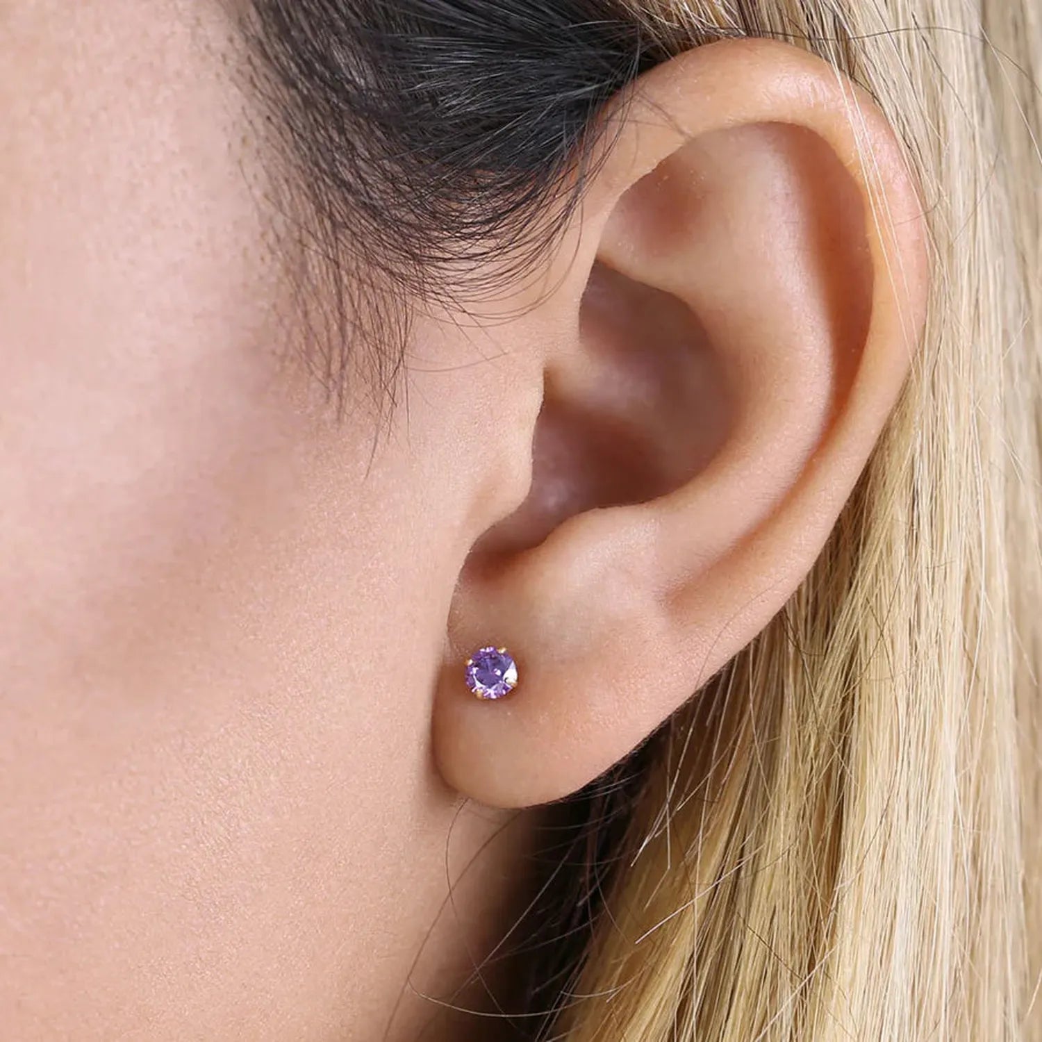 14K yellow gold amethyst CZ earrings on ear with vivid purple gemstone and polished gold setting