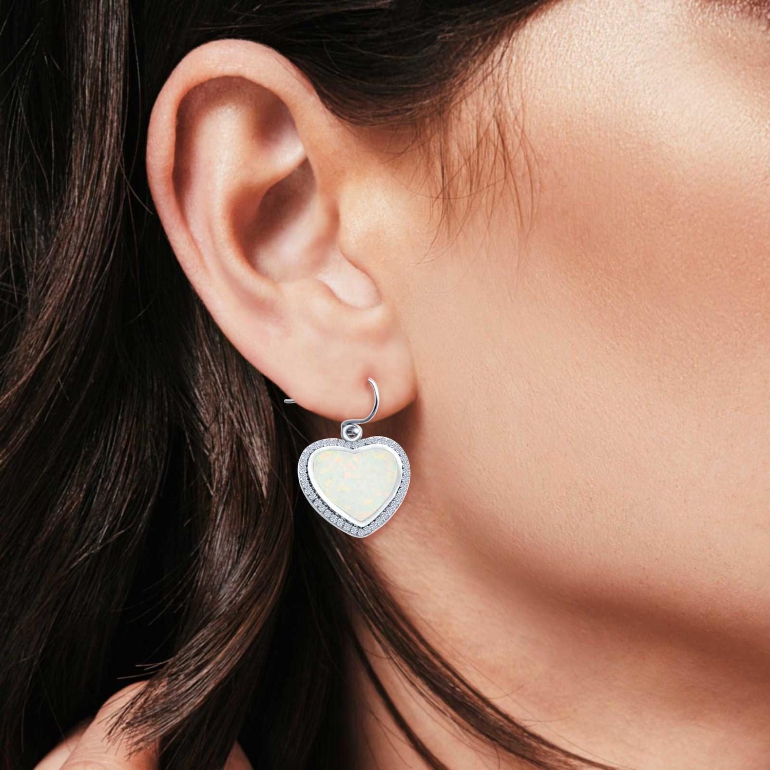 Melchior Jewellery opal heart halo earrings with iridescent white opal centre and silver halo on model's ear