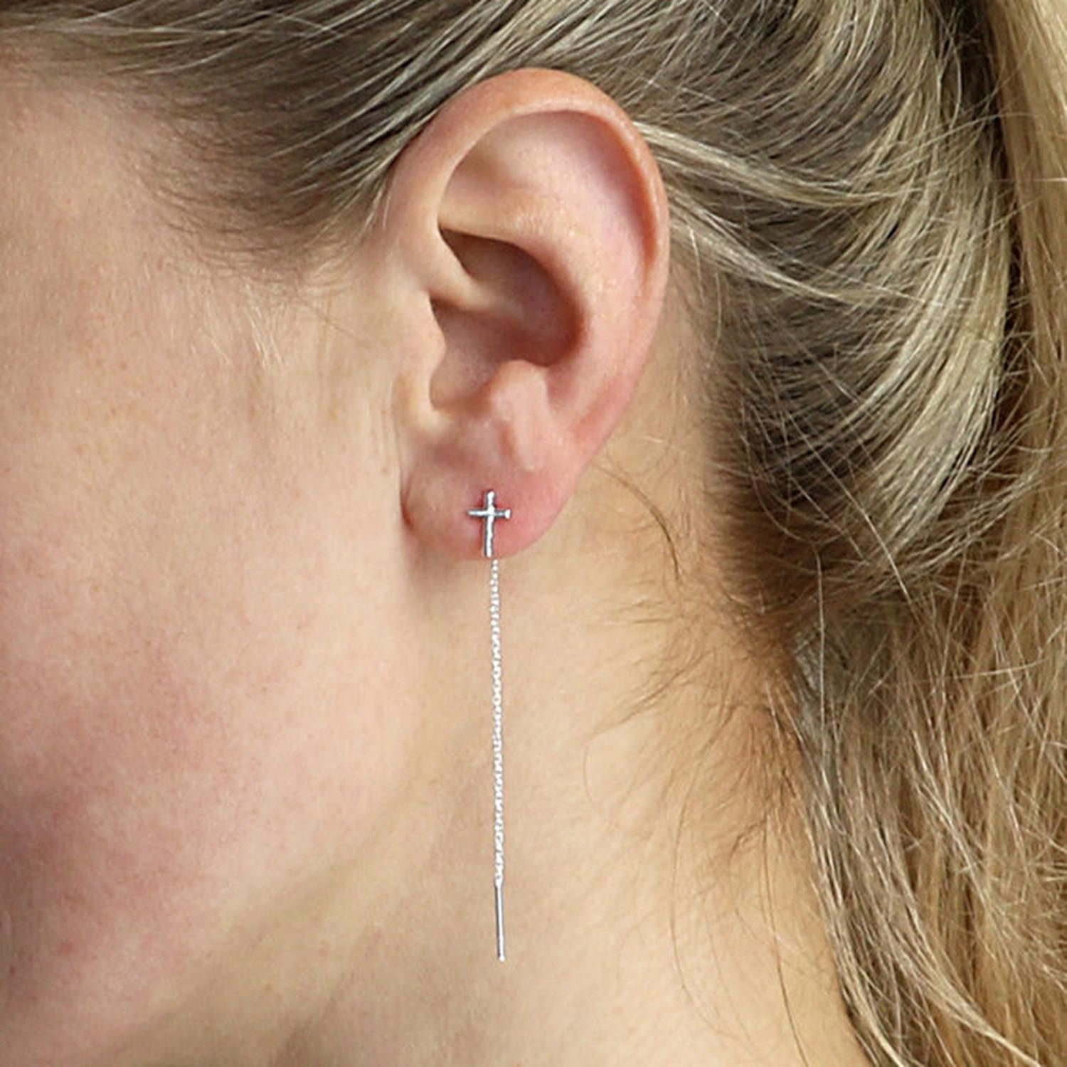 Melchior Jewellery Silver Cross Through Drop Earrings in polished silver worn on a light-skinned ear with blonde hair