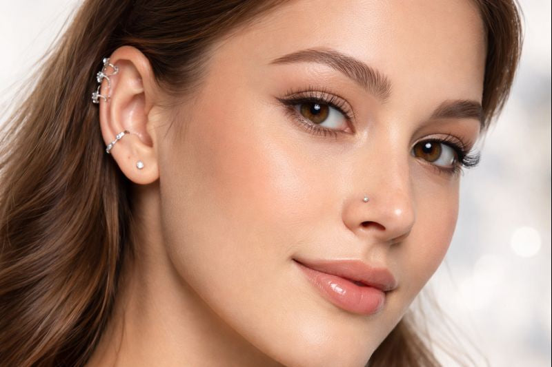 Close-up of a woman's ear adorned with sterling silver Cartilage-Tragus earrings in multiple designs including studs and hoops