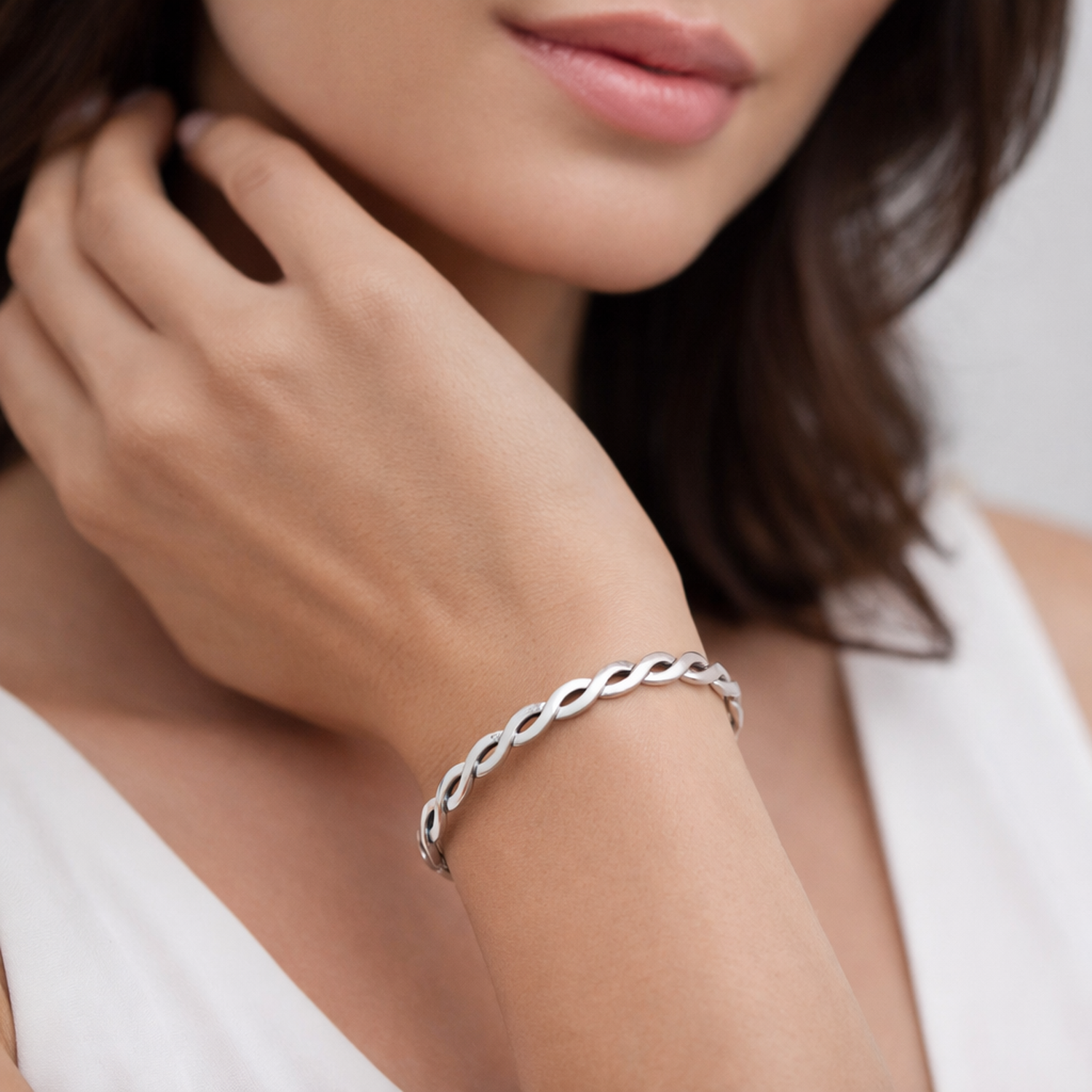 Sterling silver oxidised bangle with twisted design worn on wrist by woman from Melchior Jewellery