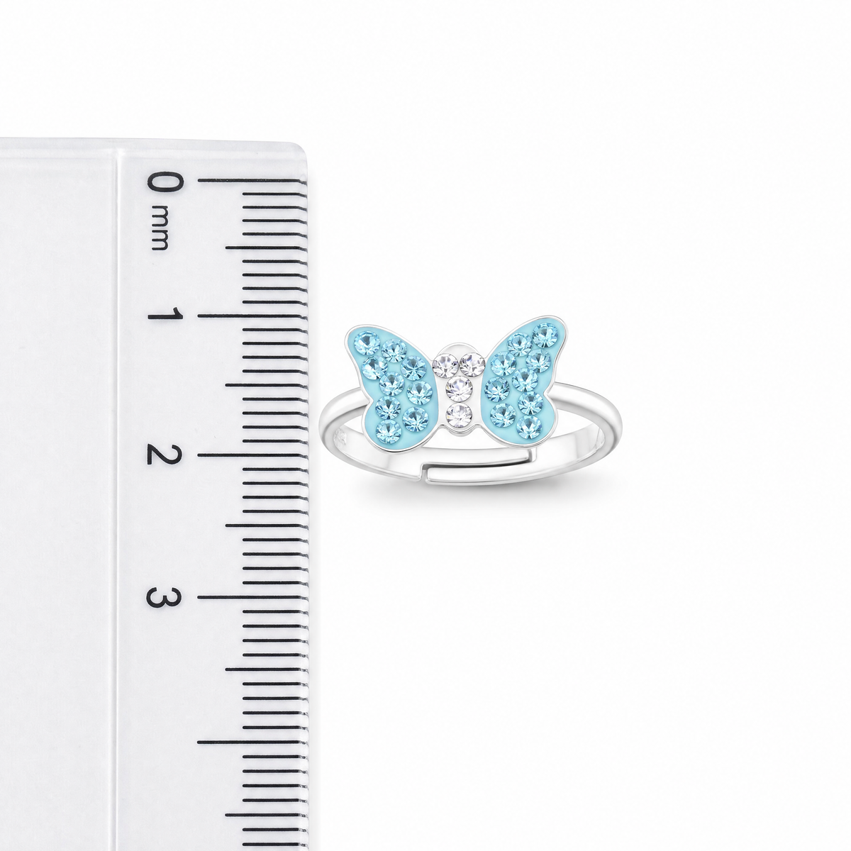 A silver butterfly ring with light blue and clear crystals, shown next to a white ruler for scale.