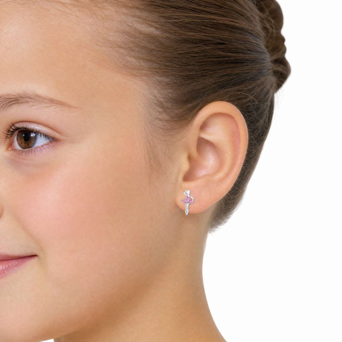 A close-up side profile of a young girl wearing pink ballerina earrings
