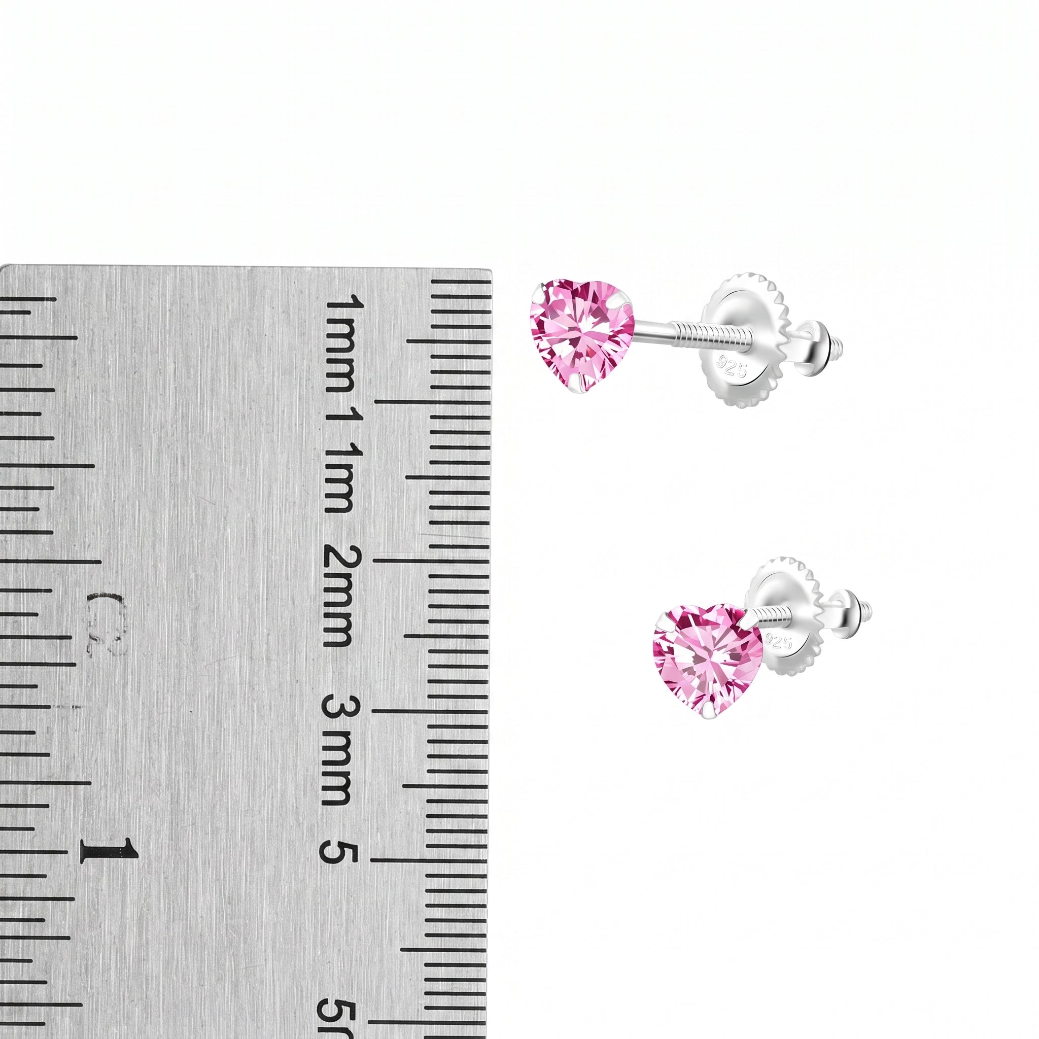A pair of silver screw back stud earrings with heart-shaped pink gemstones, shown next to a metal ruler for scale on a white background.