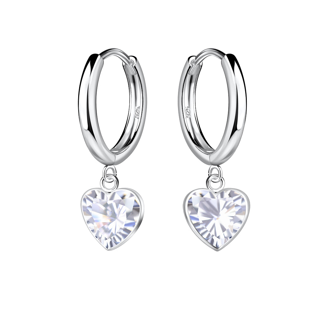 A pair of silver huggie hoop earrings with dangling heart-shaped clear crystals, shown on a solid white background.