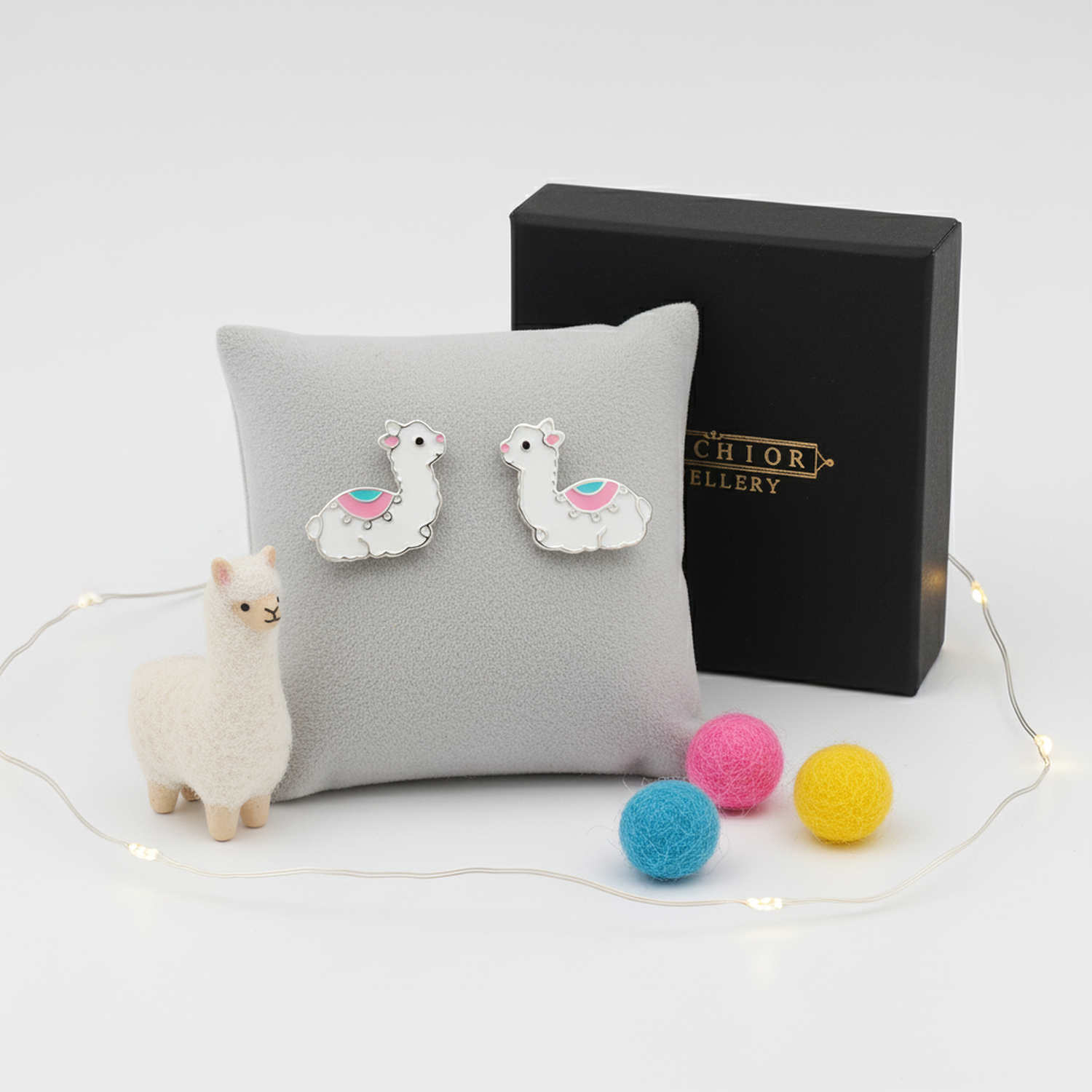 Melchior Jewellery alpaca stud earrings for kids displayed on grey cushion with gift box and colourful felt balls