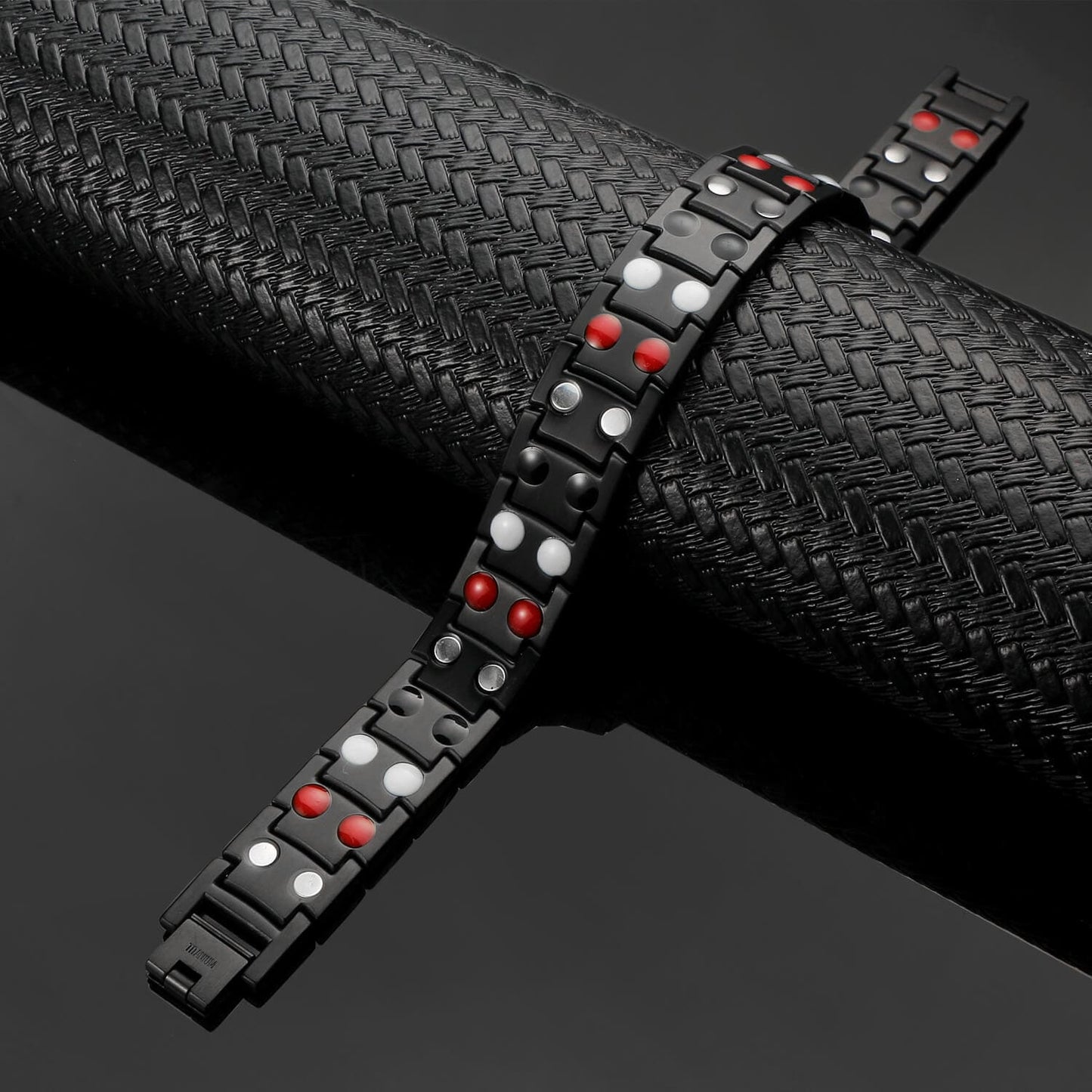 Black titanium magnetic bracelet by Melchior Jewellery featuring red and silver magnetic elements on a textured black background