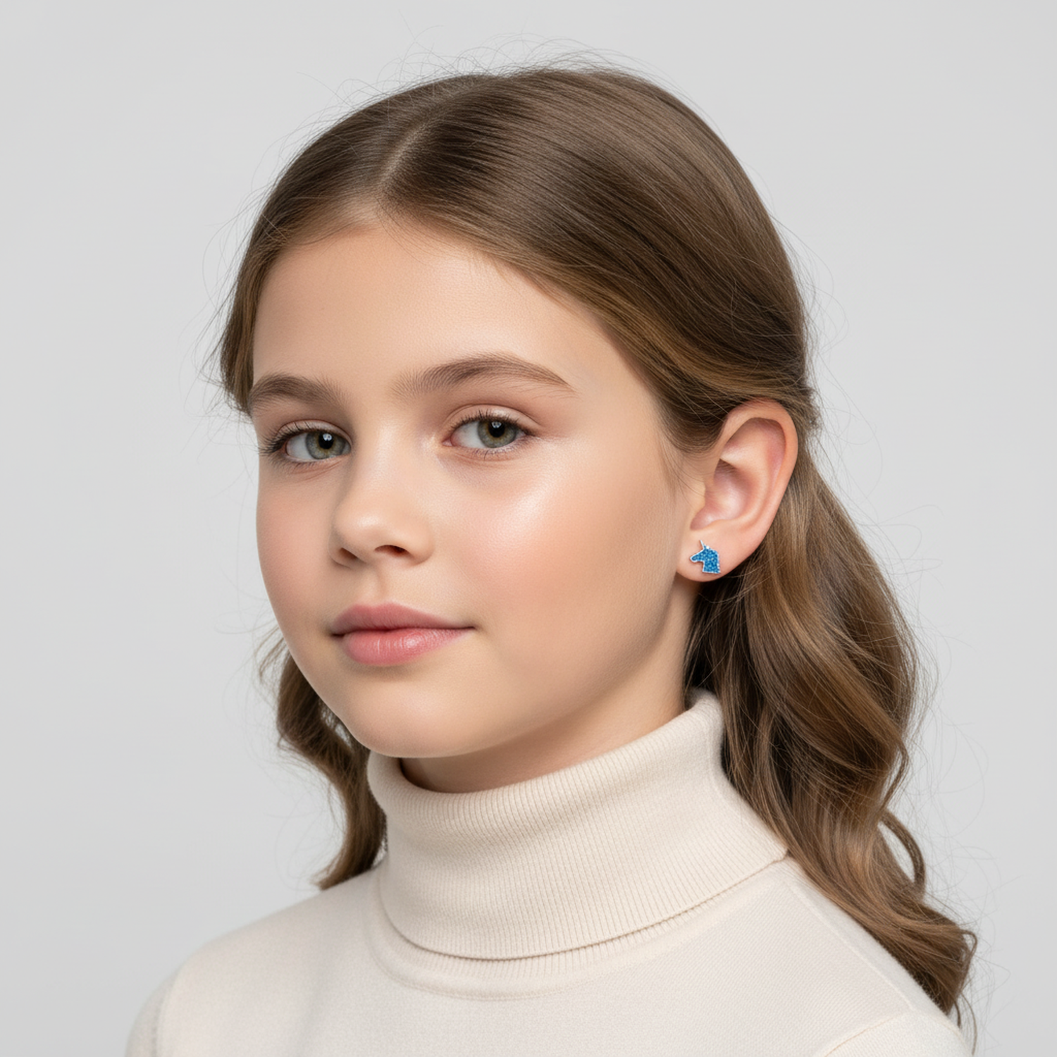 Girl wearing blue unicorn stud earrings for kids by Melchior Jewellery in a close-up portrait