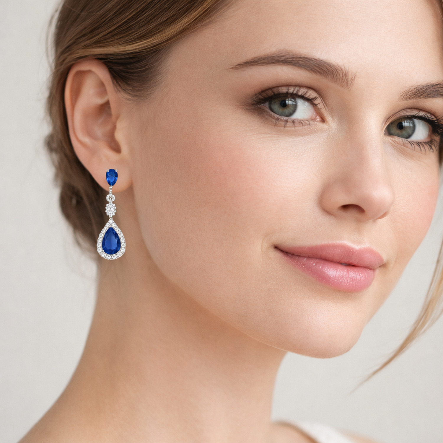 Sterling silver sapphire teardrop earrings worn by woman with light skin and blue eyes