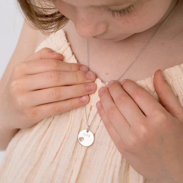 Child wearing Melchior Jewellery children's personalised heart necklace with engraved name on silver pendant