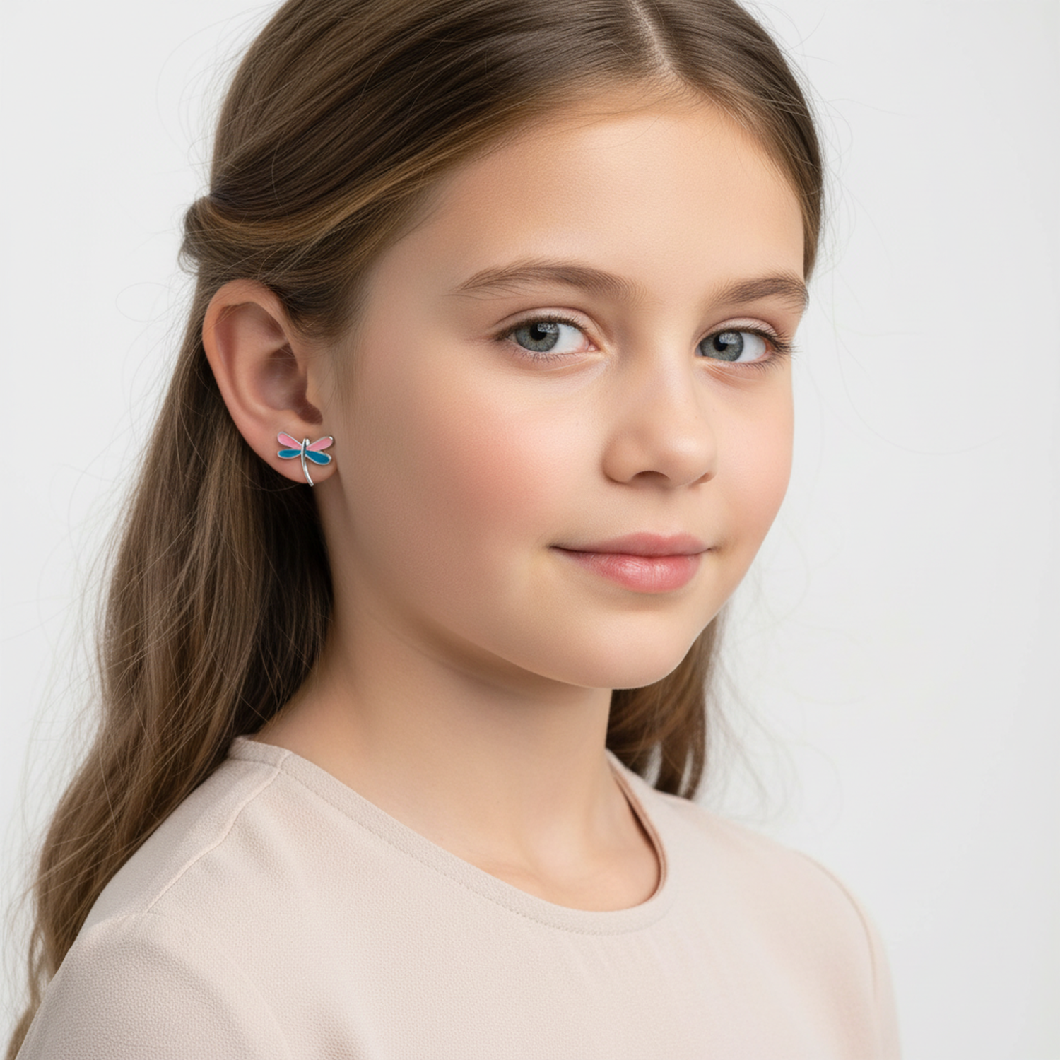 Young girl wearing pink and blue dragonfly stud earrings for kids by Melchior Jewellery