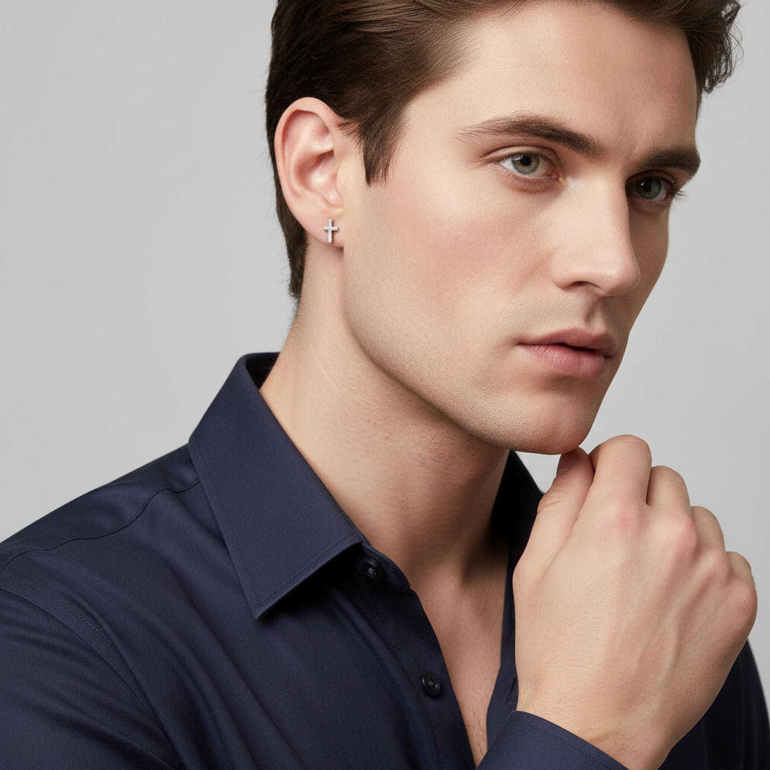 Sterling silver mens cross stud earring worn by man in navy shirt with thoughtful expression
