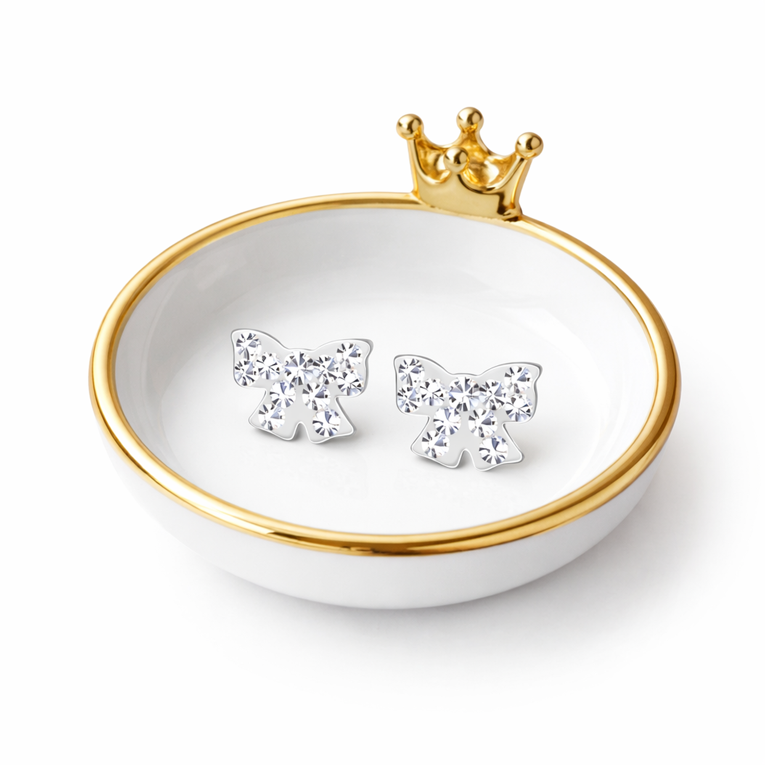Crystal bow earrings for kids by Melchior Jewellery displayed on a white dish with gold trim and crown detail