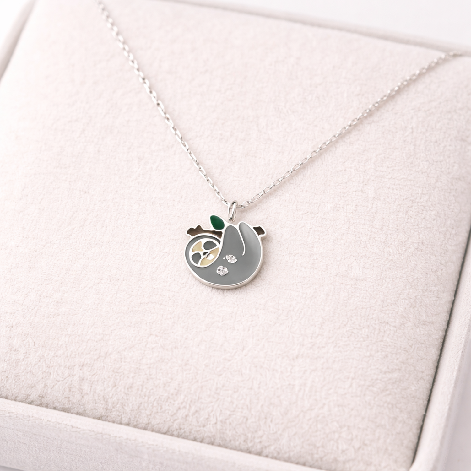 Sterling silver sloth necklace for kids by Melchior Jewellery displayed on soft cushion