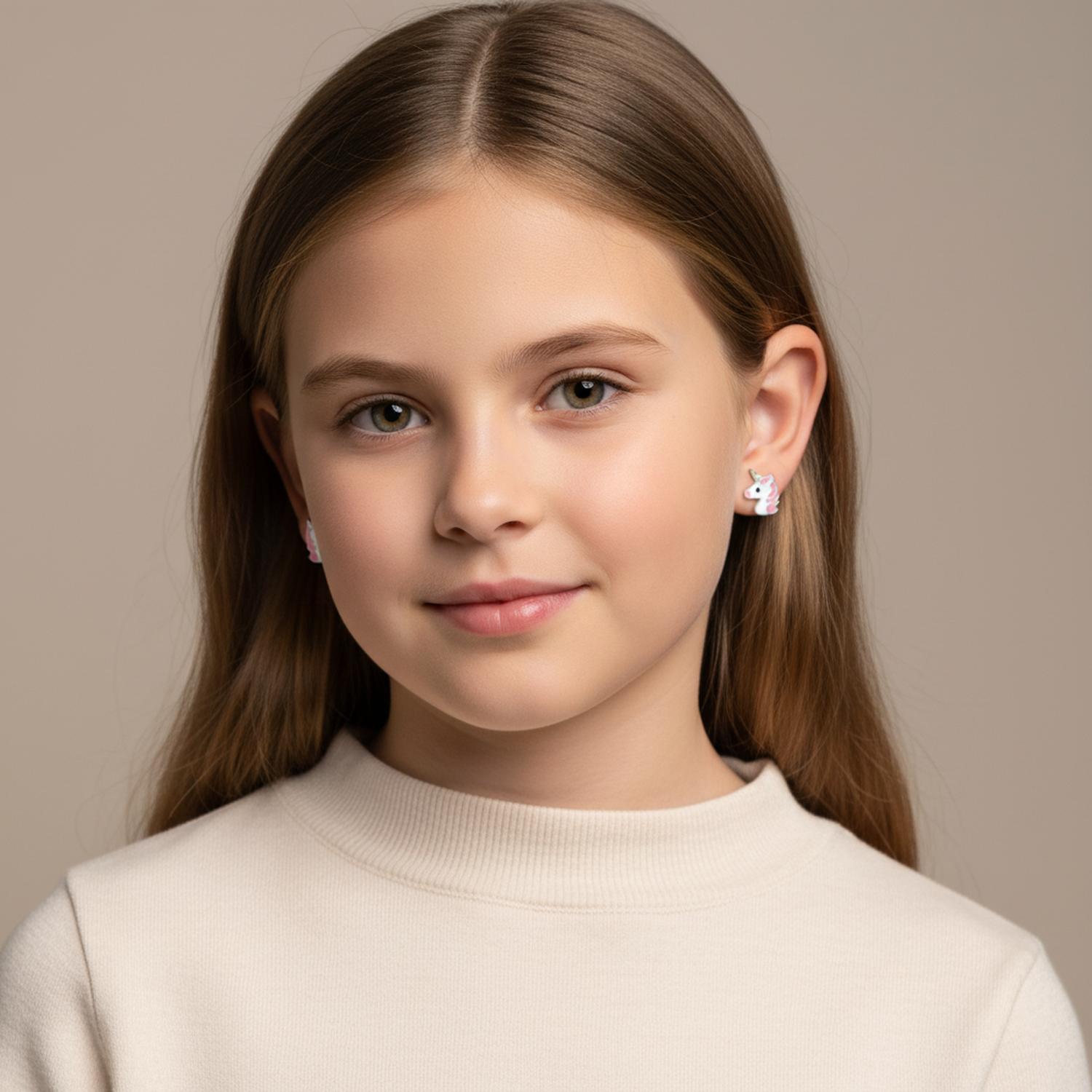 Young girl wearing pink unicorn stud earrings for children by Melchior Jewellery with beige background
