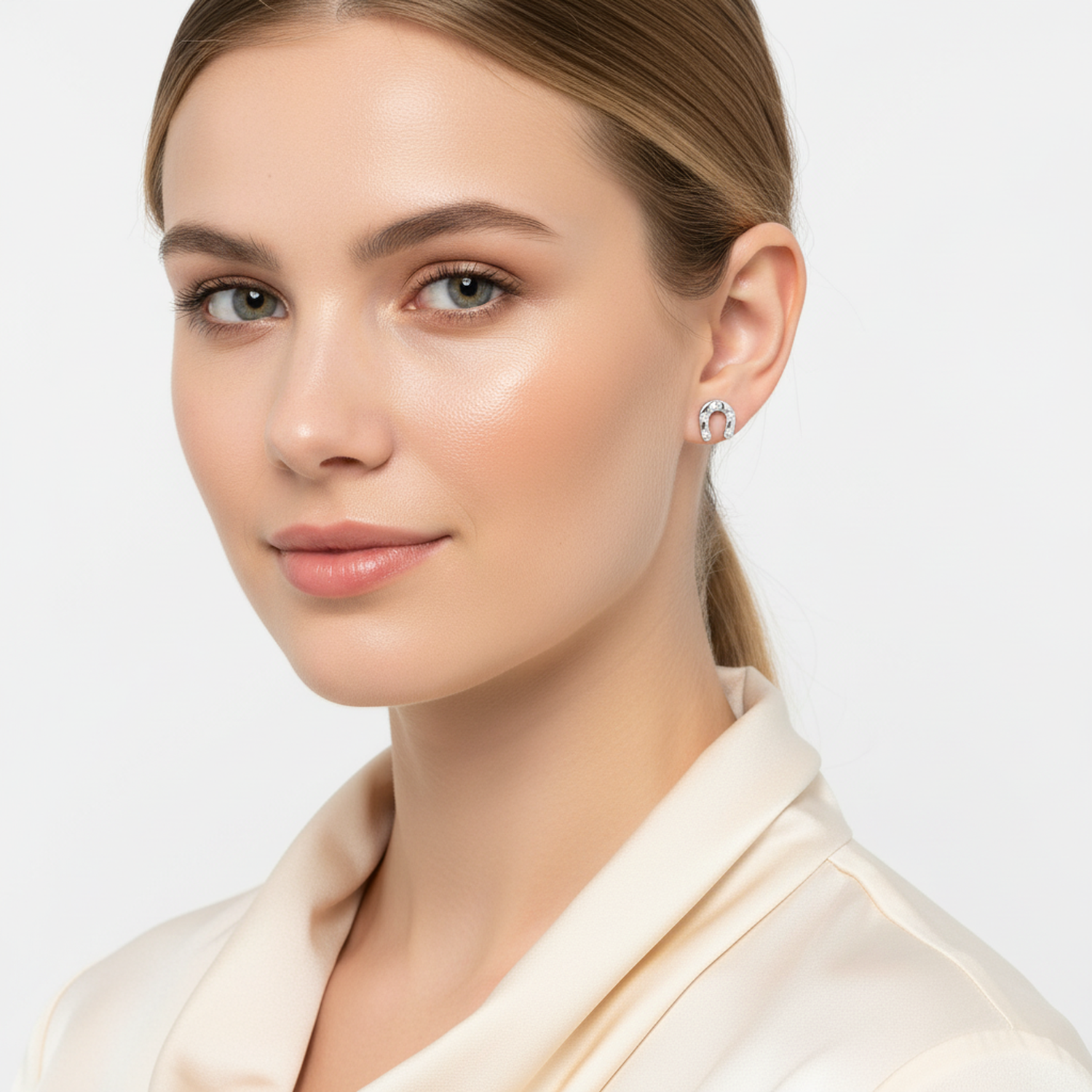 Sterling silver horseshoe earrings worn by woman with smooth skin and cream blouse from Melchior Jewellery