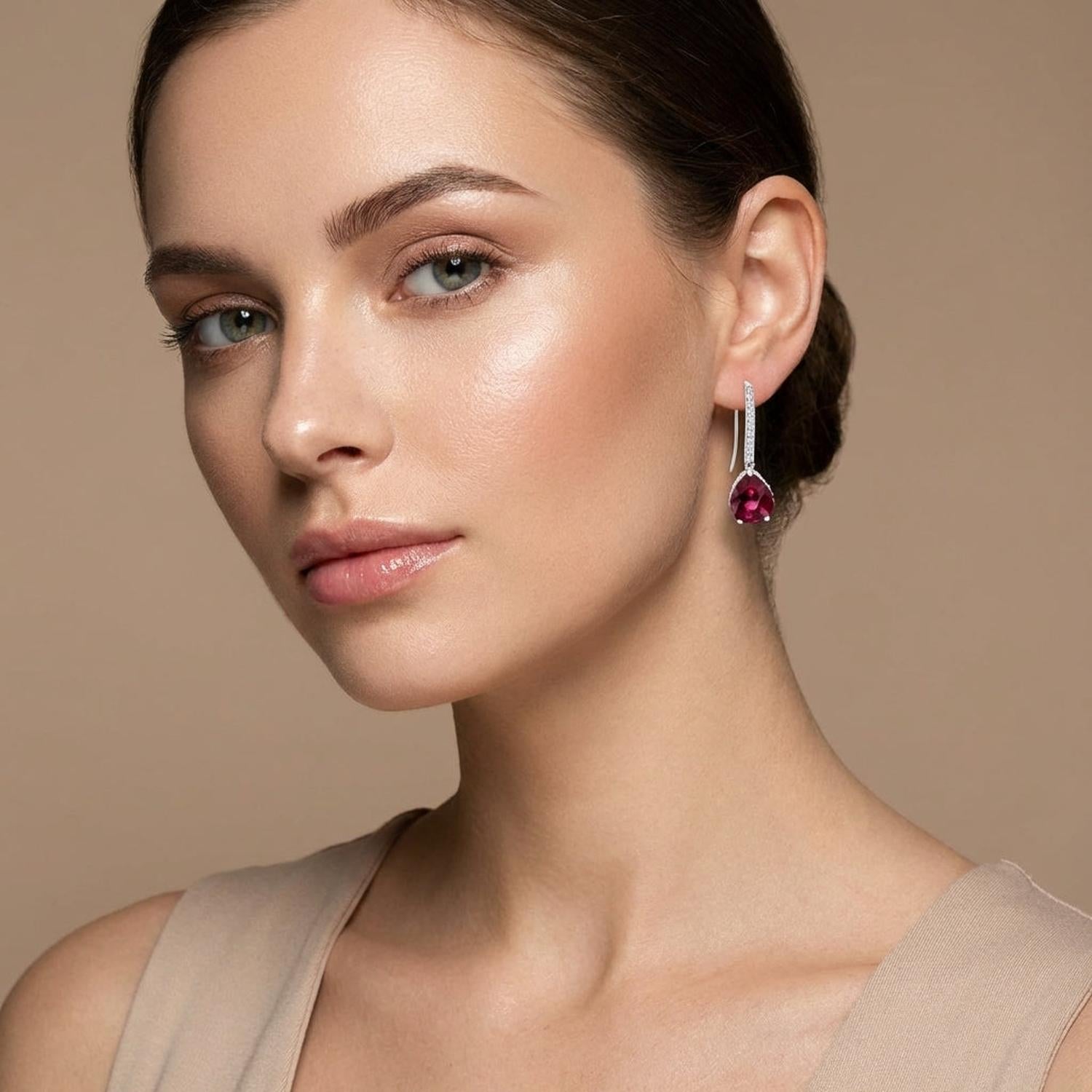Elegant ruby red drop earrings with silver detailing worn by woman with smooth skin and dark hair