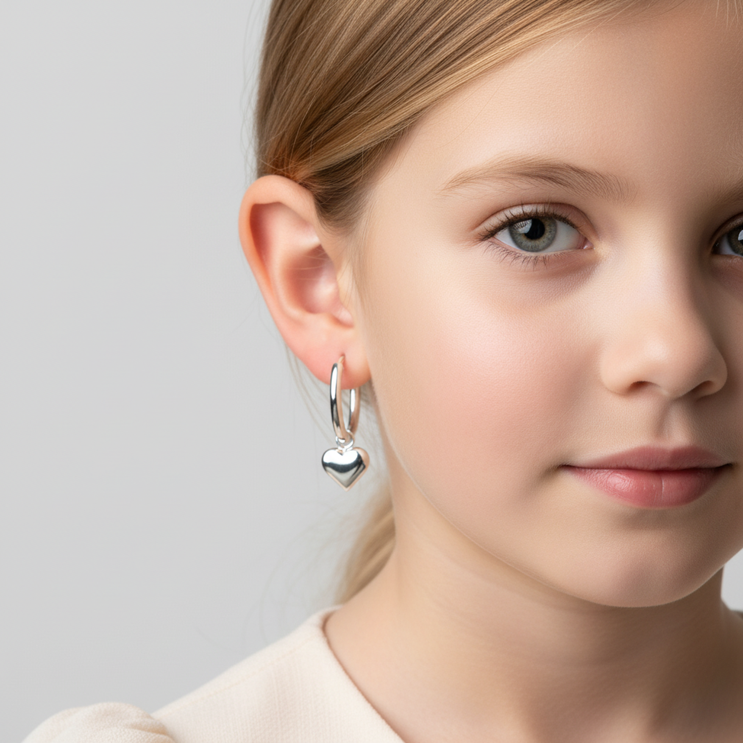 Girls silver hoop earrings with heart charm worn by young girl from Melchior Jewellery