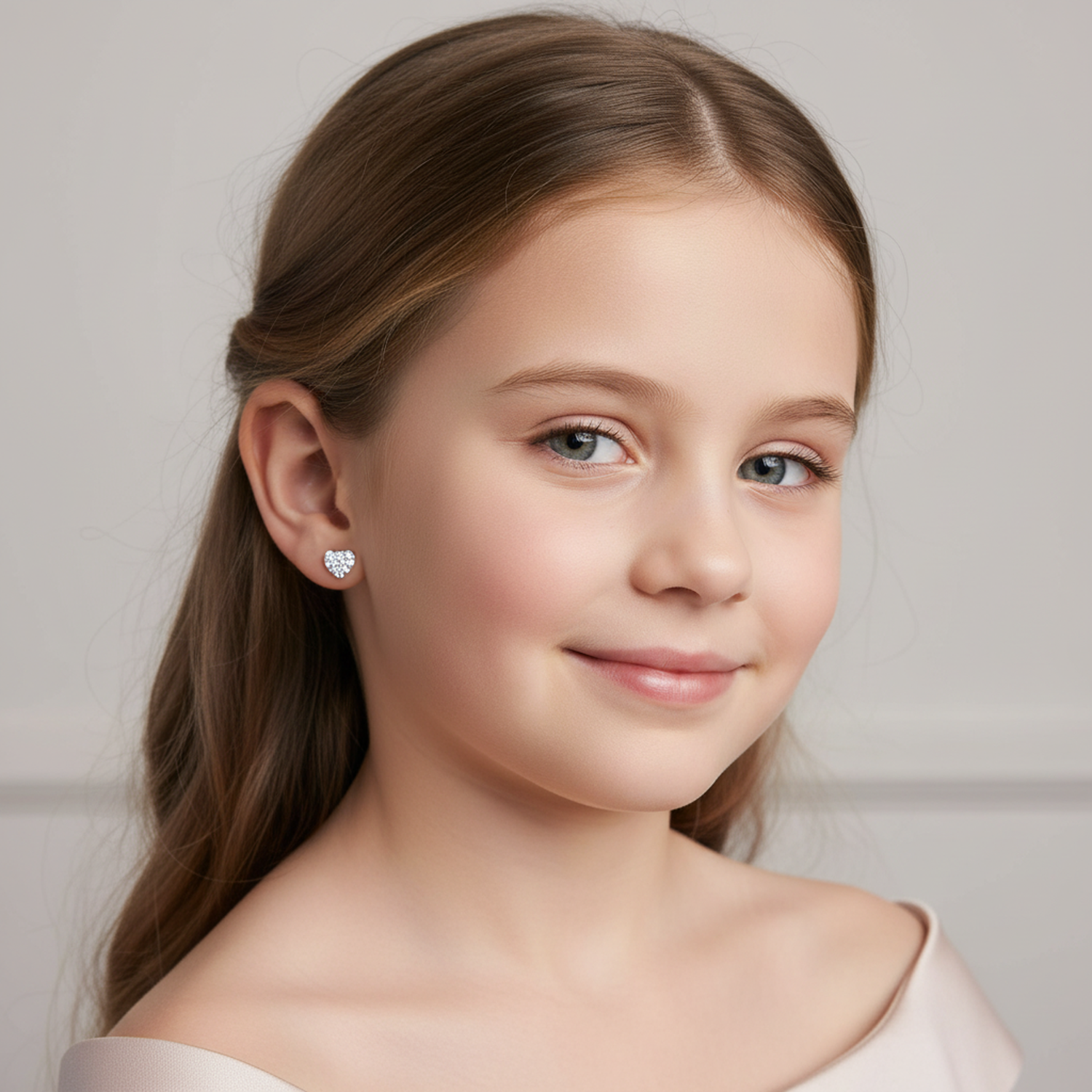 Young girl wearing silver girls heart earrings with sparkling clear stones from Melchior Jewellery