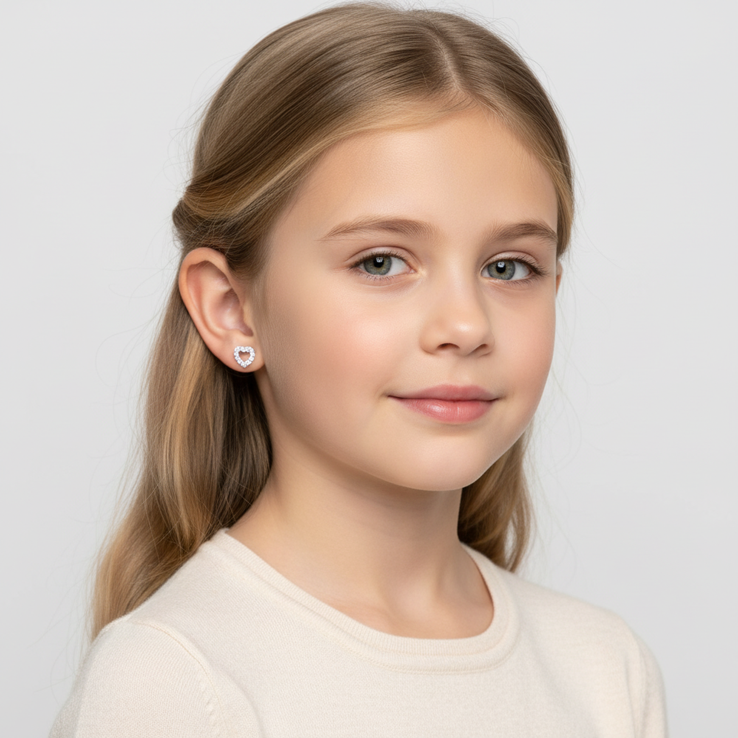 Sterling silver heart earrings for girls worn by smiling young girl with blonde hair and cream top