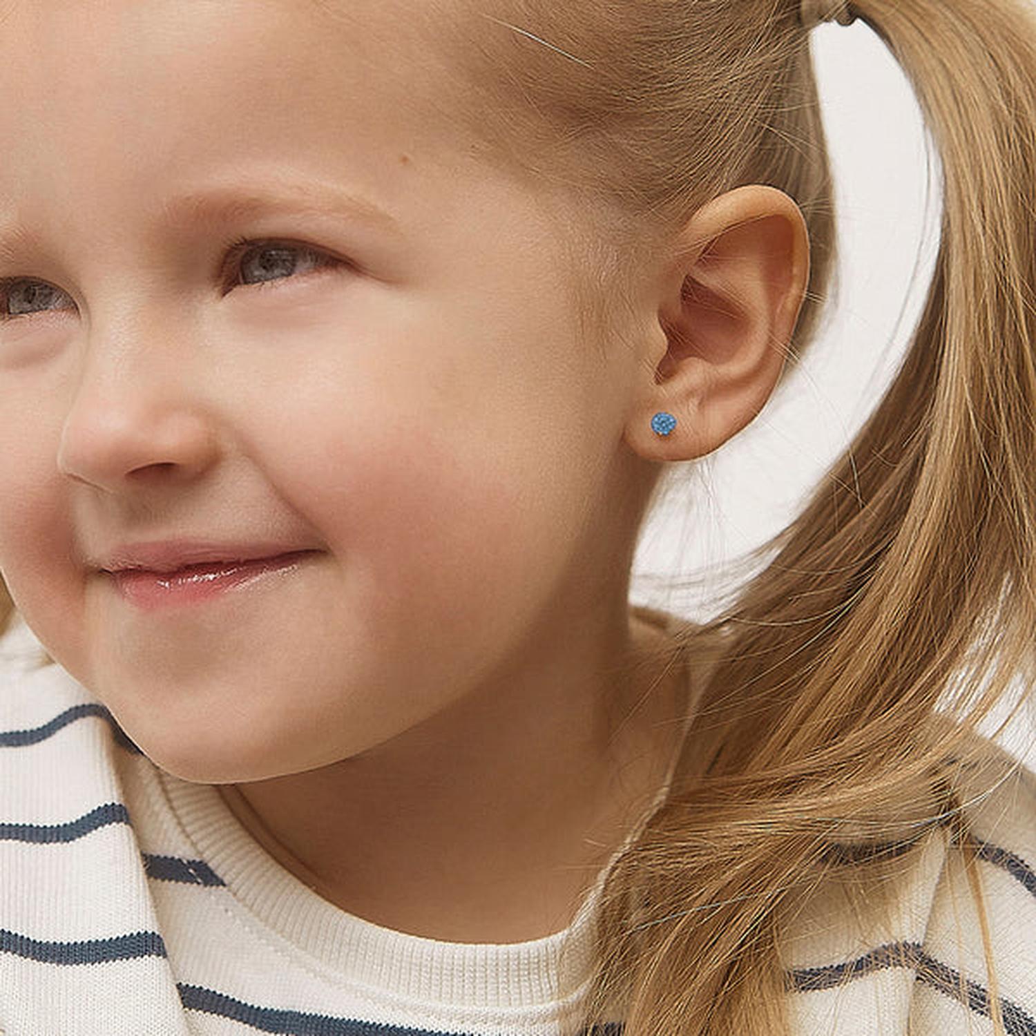 14k gold December birthstone earrings in blue worn by a young girl by In Season Jewellery