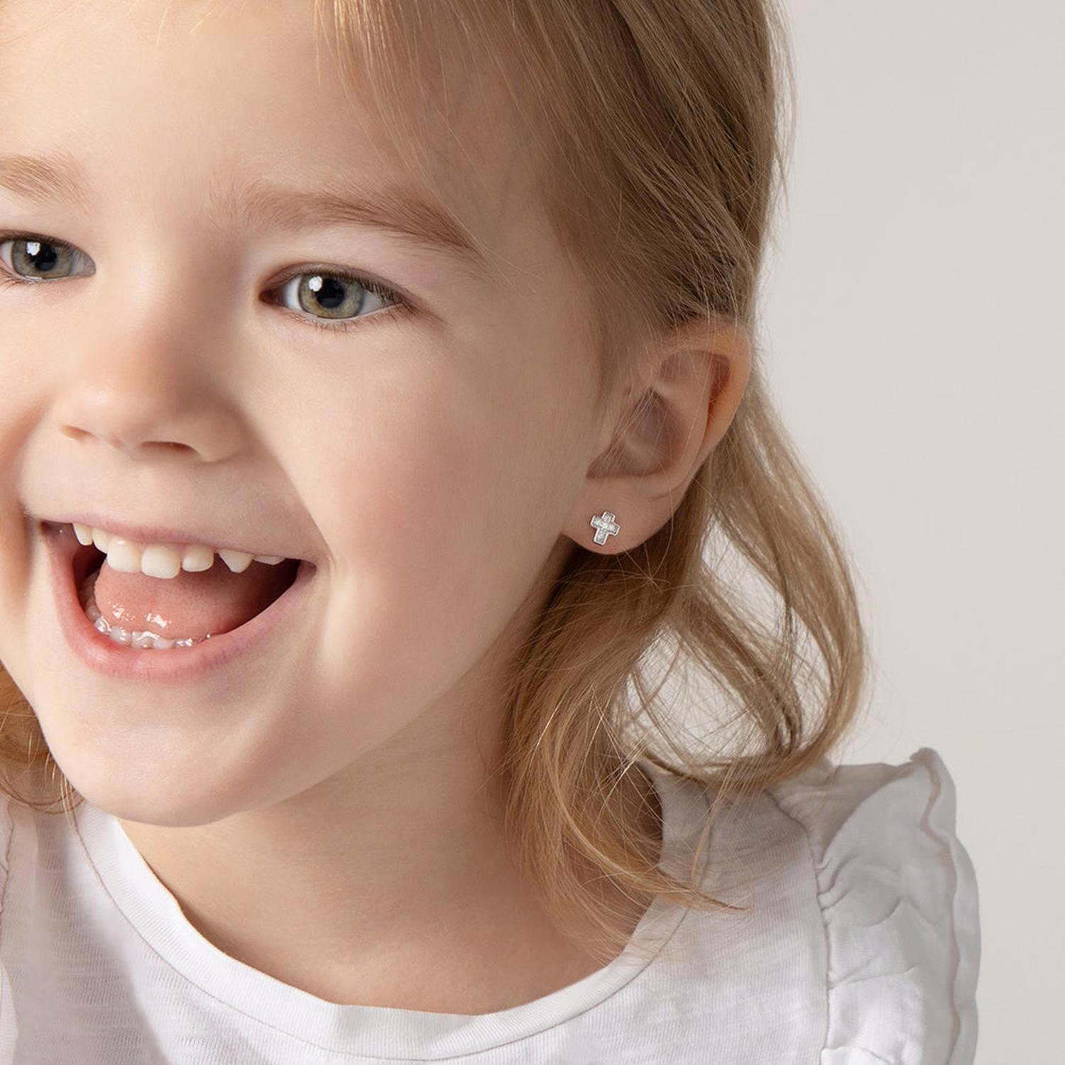 Young girl wearing silver Girls CZ Cross Screw Back Earrings with white cubic zirconia stones by In Season Jewellery