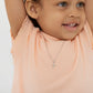 Girls sterling silver cross necklace and earrings worn by smiling girl in peach top from Melchior Jewellery