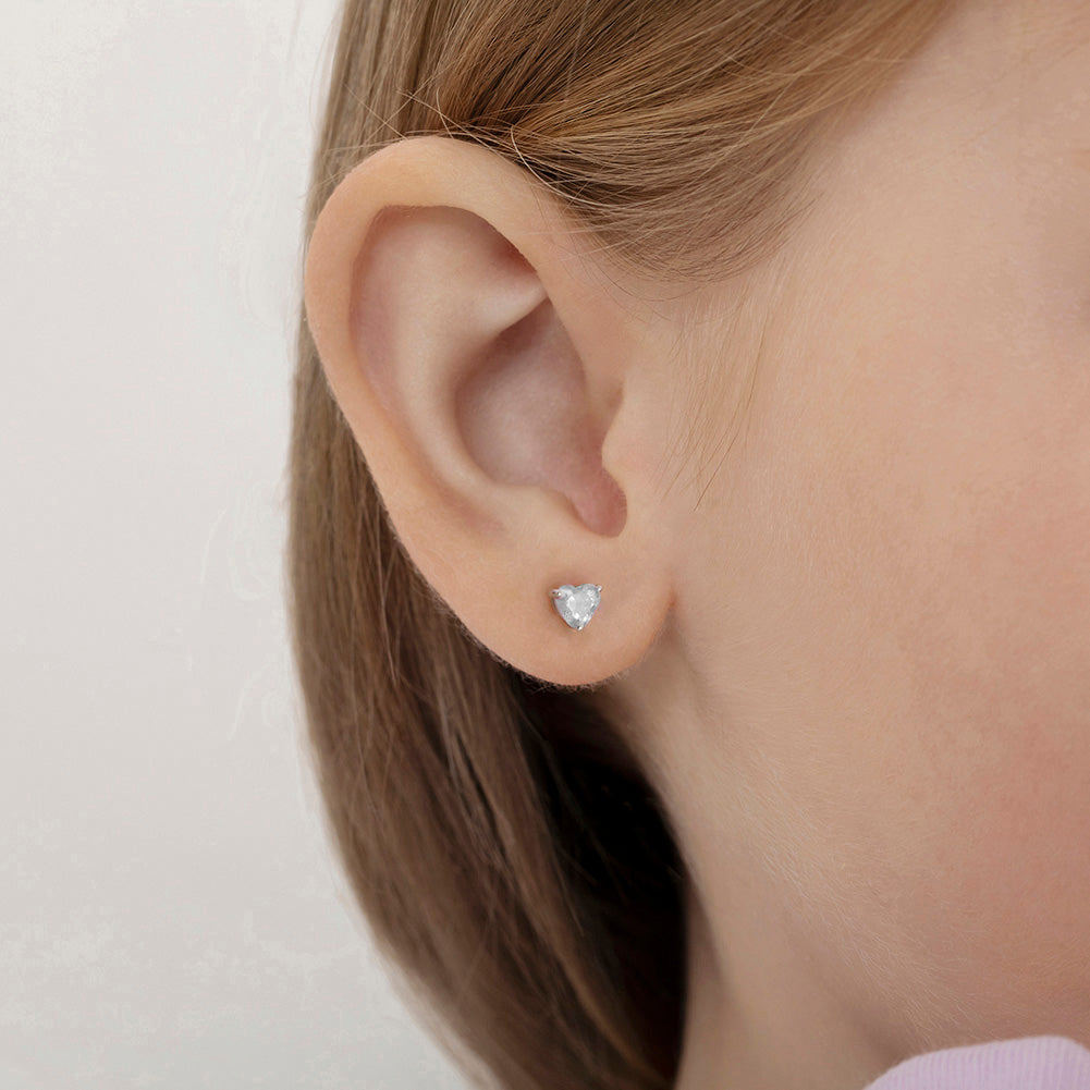 In Season Jewellery children's sterling silver heart earrings worn on a young girl's ear