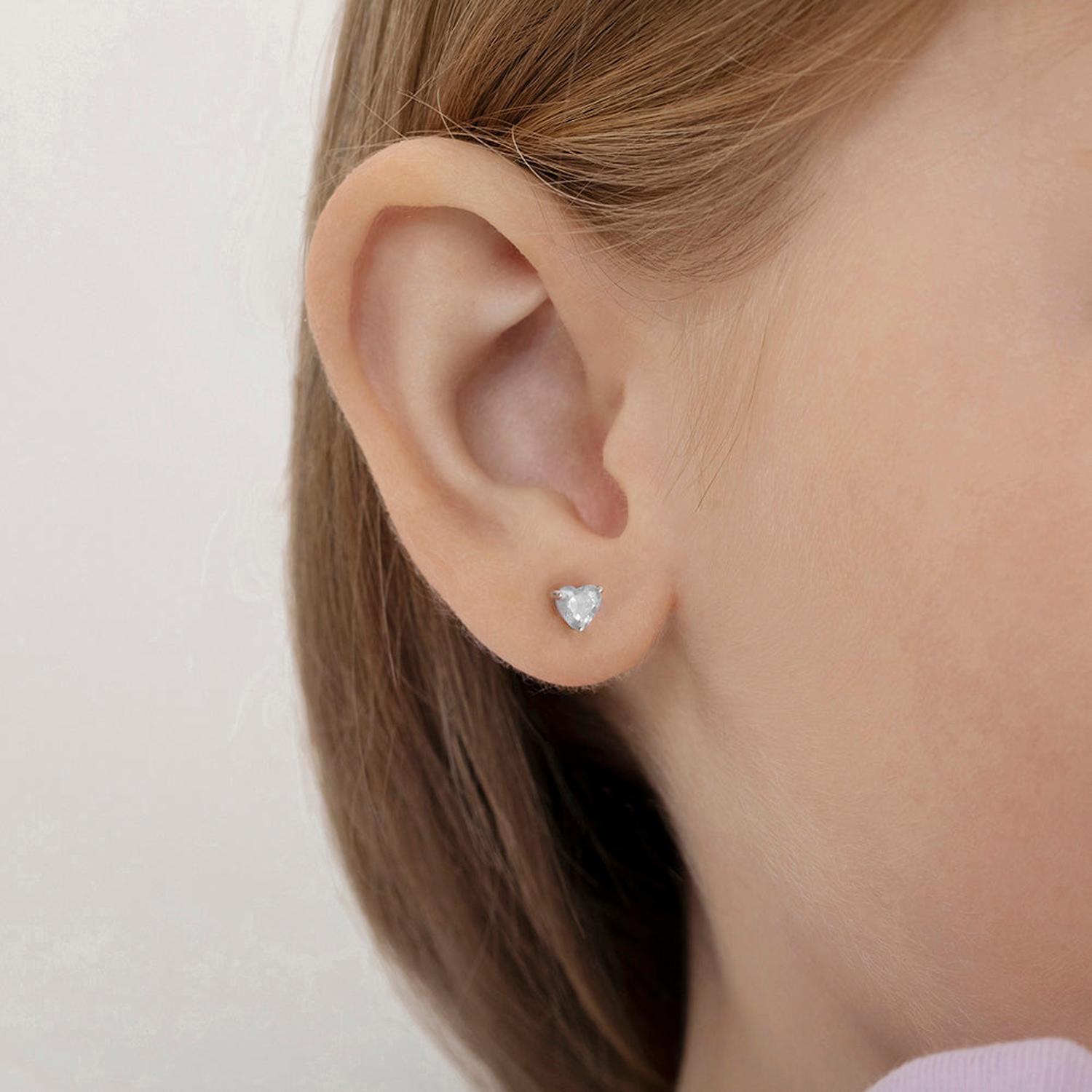 In Season Jewellery children's sterling silver heart earrings worn on a young girl's ear