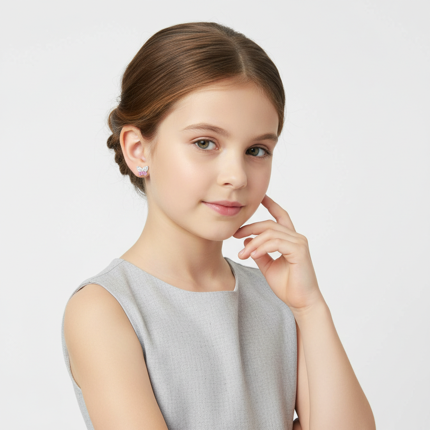 Young girl wearing kids butterfly earrings with crystals from Melchior Jewellery in a grey dress