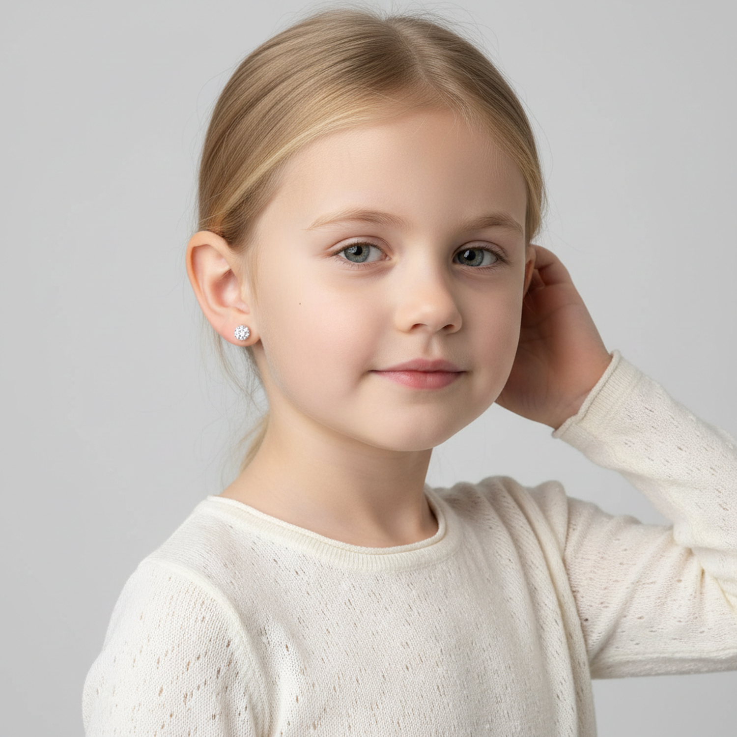 Young girl wearing Melchior Jewellery kids crystal ball stud earrings in silver with a white top