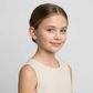 Young girl wearing kids heart-shaped silver earrings from Melchior Jewellery with pink detailing