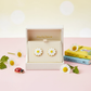 14ct gold plated daisy earrings for girls by Melchior Jewellery displayed in cream box with daisies and books