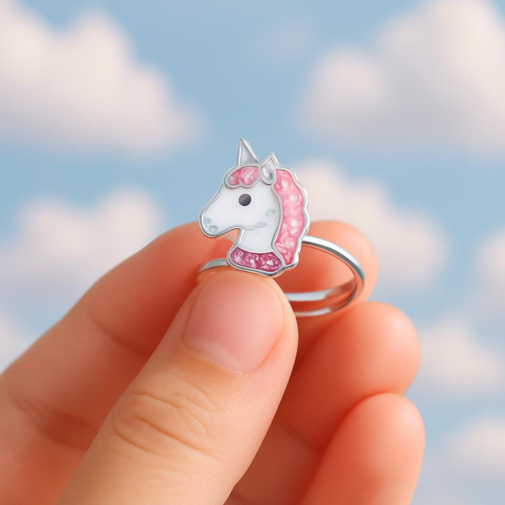 Melchior Jewellery adjustable unicorn ring for kids with pink and white enamel detail held against a sky background
