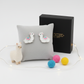 Melchior Jewellery alpaca stud earrings for kids displayed on grey cushion with gift box and colourful felt balls